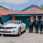 White Chevrolet car with groom and groomsmen